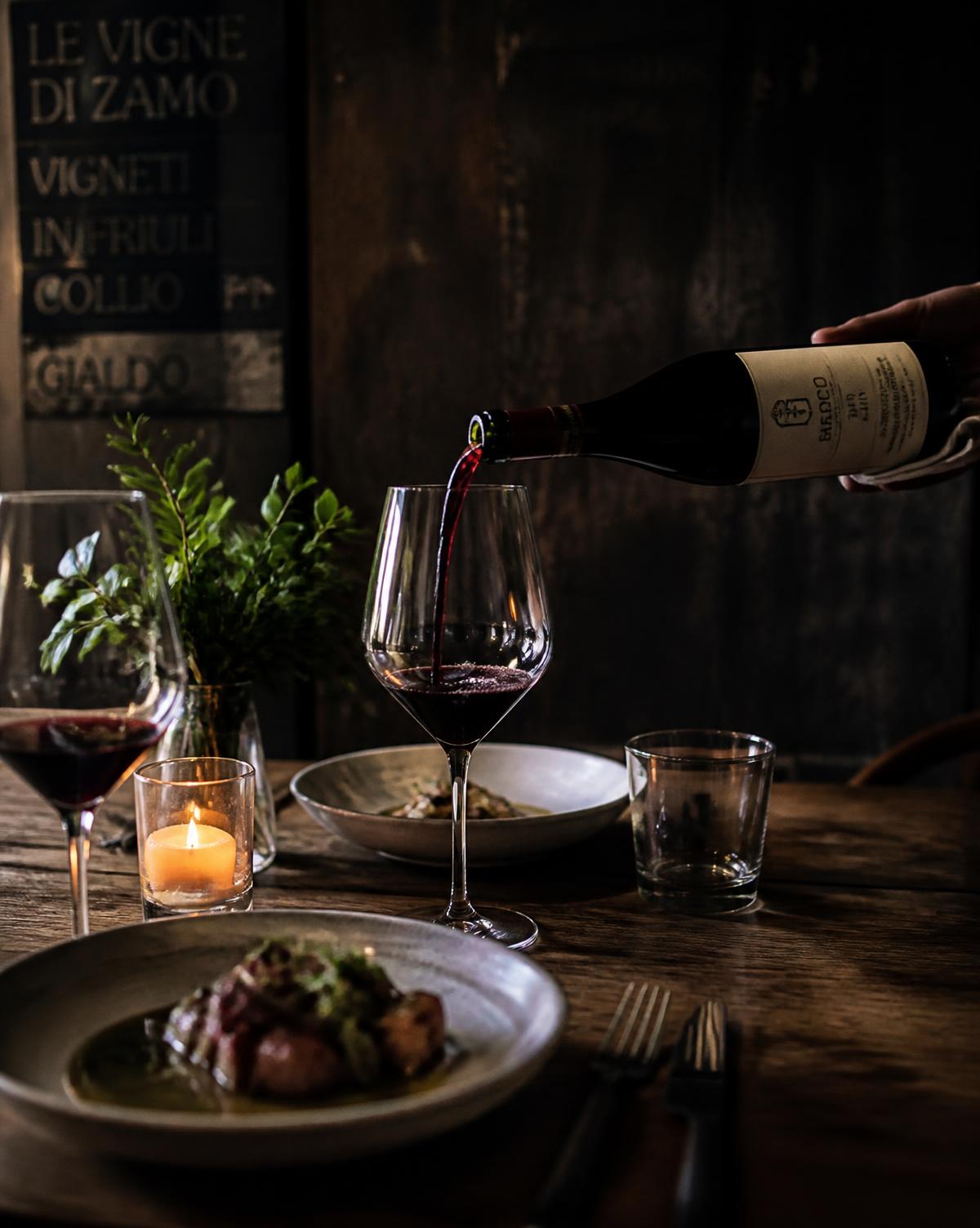 Rotwein wird am Tisch eingeschenkt